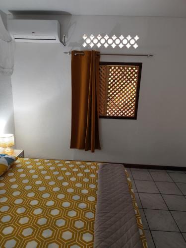 a bedroom with a bed and a window with curtains at MO TI KOTÉ in Cayenne