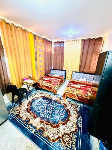 a bedroom with two beds and a rug at MKB APARTMENTS in Abu Dhabi