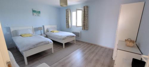 Habitación con 2 camas, paredes azules y suelo de madera. en Les fins bois, en Gondeville