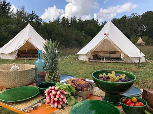 une table avec de la nourriture et des tentes dans un champ dans l'établissement Kârma Hôtel, à Saint-Germain-Laval