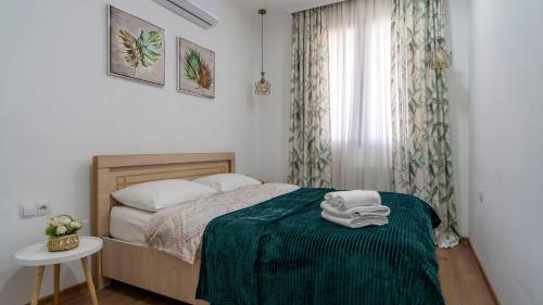 1 dormitorio con 1 cama con manta verde y ventana en One-bedroom apartments in Tbilisi Gardens, en Tiflis
