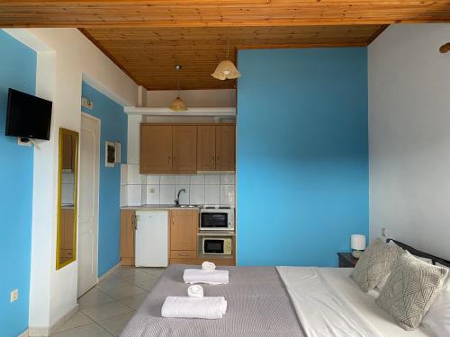 een blauwe kamer met een bed en een keuken bij Albatros rooms in Vathi