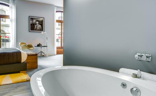 a bathroom with a white tub and a bed at Hotel Gault in Montréal