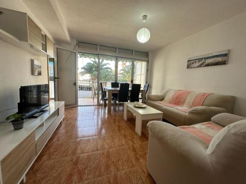 - un salon avec un canapé, une télévision et une table dans l'établissement Haro Beach San Juan, à El Campello
