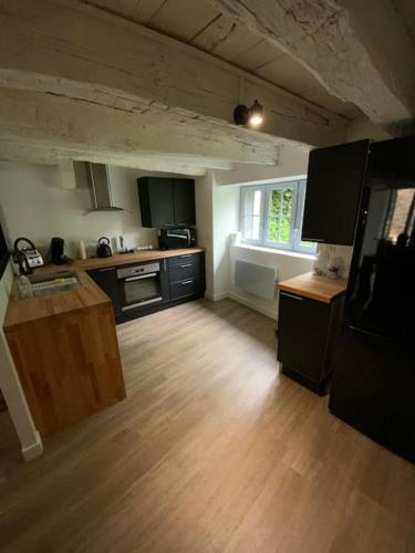 une cuisine avec des armoires noires et un plancher en bois dans l'établissement Sarlat centre historique. Maison de ville, à Sarlat-la-Canéda