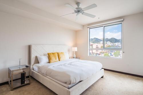 ein weißes Schlafzimmer mit einem Bett und einem Fenster in der Unterkunft Comfortable 2Bed 2Bath Apt in West Hollywood in Los Angeles