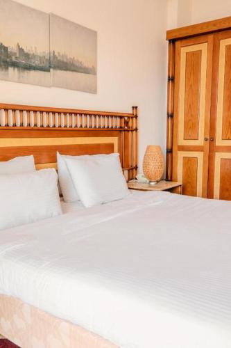 a bedroom with a large white bed with a wooden headboard at Umm Kulthum Hotel in Cairo