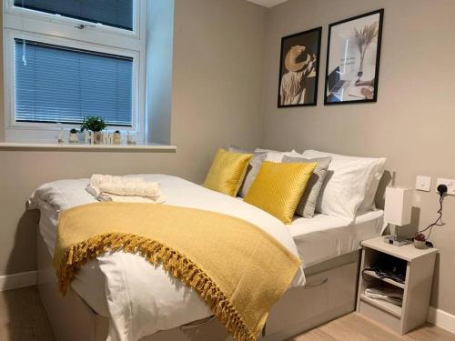 una camera da letto con un letto con cuscini gialli e bianchi di HNFC Stays - Prime Central Newcastle Studio w/ Gym+Free parking a Newcastle upon Tyne
