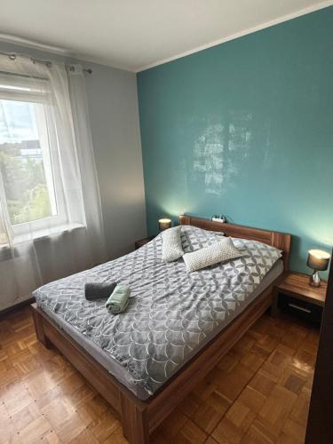 a bedroom with a bed with a blue wall at Apartament 18 in Toruń