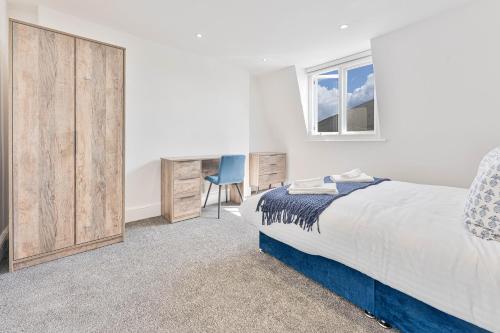 1 dormitorio con cama, escritorio y ventana en The Residence by Guestz, en Cheltenham