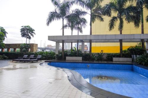 a swimming pool in front of a building with palm trees at Free Parking- Good for 4pax Makati Condo near CBD in Manila
