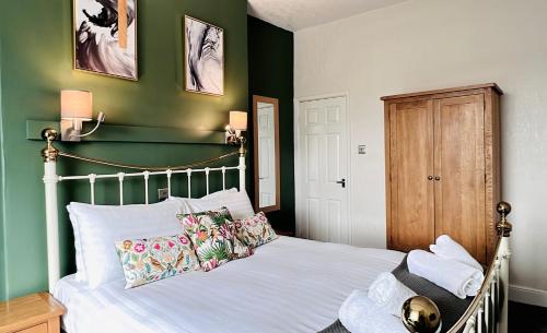 a bedroom with a white bed with a green wall at The Kendrick Exclusively for adults in Llandudno