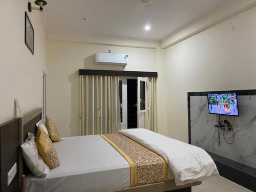 a bedroom with a bed with a tv on the wall at Hotel Nath Palace Chunar Road Varanasi - Luxury Room - Excellent Service Recommended in Varanasi