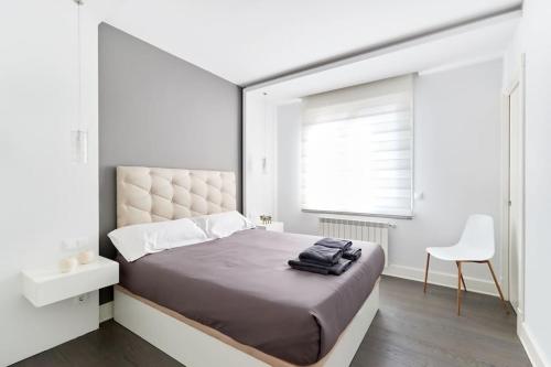 a white bedroom with a large bed and a white chair at Tranquilo Apartamento en pleno corazón de Pamplona in Pamplona