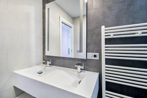 y baño con lavabo blanco y espejo. en Tranquilo Apartamento en pleno corazón de Pamplona en Pamplona