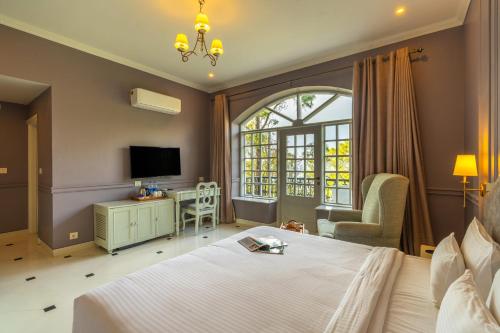 a bedroom with a bed and a chair and a tv at StayVista at The Mansion in Kasauli