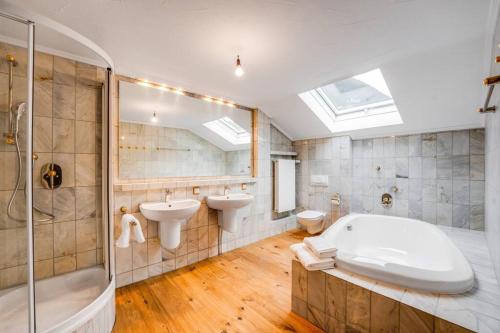 a bathroom with a tub and two sinks and a shower at Felder´s - Chalet Infinity - Neueröffnung in Burgberg
