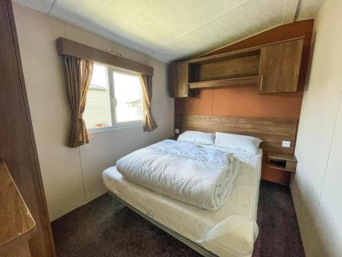 Habitación pequeña con cama y ventana en Lovely 8 Berth Caravan At California Cliffs Nearby Scratby Beach Ref 50060e, en Great Yarmouth