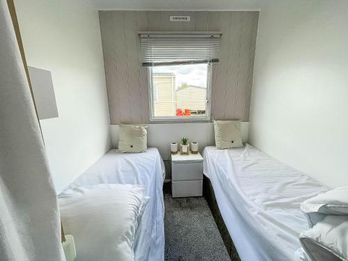 two beds in a small room with a window at Lovely 8 Berth Caravan With Wifi At Dovercourt Holiday Park Ref 44002d in Great Oakley