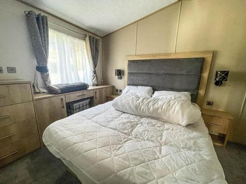 Un dormitorio con una gran cama blanca y una ventana en Beautiful Caravan With Decking And Wifi At Azure Sea, Suffolk Ref 32025az en Lowestoft