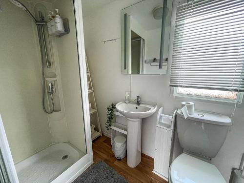 a bathroom with a sink and a toilet and a mirror at Lovely 8 Berth Caravan With Wifi At Dovercourt Holiday Park Ref 44002d in Great Oakley