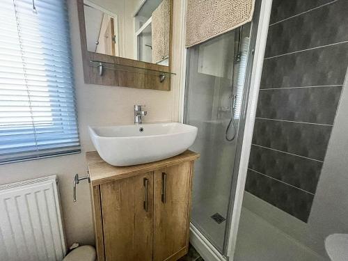 y baño con lavabo y ducha. en Beautiful Caravan With Decking And Wifi At Azure Sea, Suffolk Ref 32025az en Lowestoft