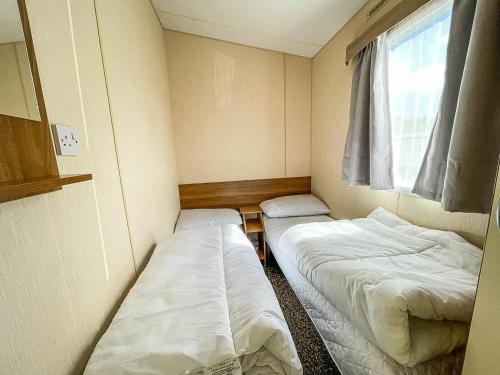 two beds in a small room with a window at 8 Berth Caravan At Dovercourt Holiday Park In Essex Ref 44002p in Great Oakley