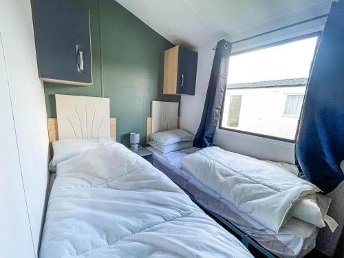 two beds in a room with a window at 6 Berth Caravan With Free Wi-fi At Dovercourt Holiday Park In Essex Ref 44009c in Great Oakley