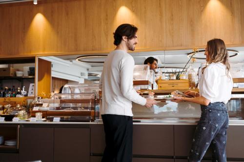 two people standing in a kitchen preparing food at THE ONE CAORLE - Hotel & Apartments in Caorle