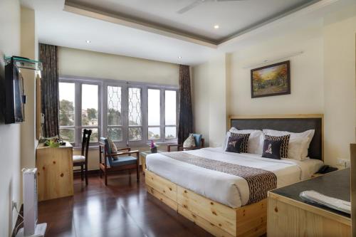 a bedroom with a large bed and a desk and window at Hotel SunGrace in Mussoorie