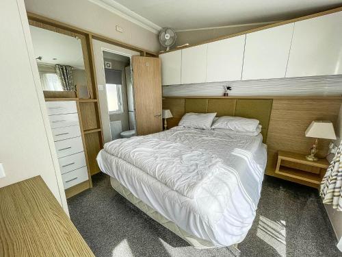 a bedroom with a large bed and white cabinets at Beautiful 6 Berth Caravan With Decking At Dovercourt Park, Essex Ref 44009g in Great Oakley