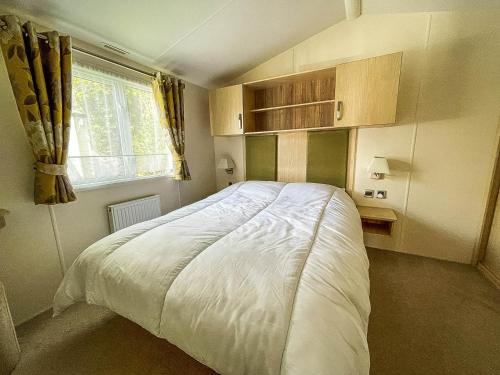 een slaapkamer met een groot wit bed en een raam bij Gorgeous 6 Berth Caravan With Decking Area, Dovercourt Holiday Park Ref 44010af in Great Oakley