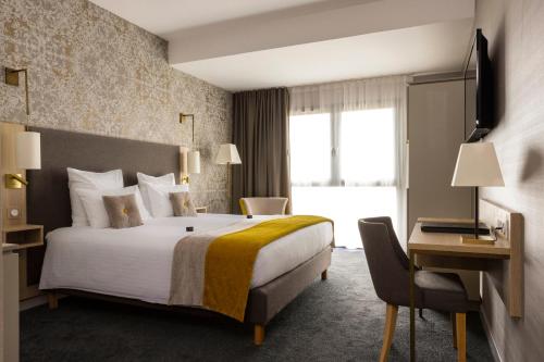 コルマールにあるJames Boutique Hôtel Colmar centreの大きなベッドとデスクが備わるホテルルームです。