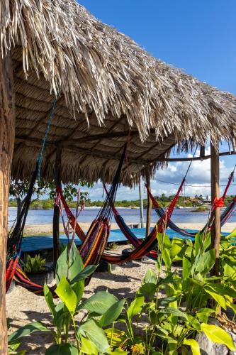 a group of hammocks under a straw hut on the beach at Pousada Sol de Amaro in Santo Amaro
