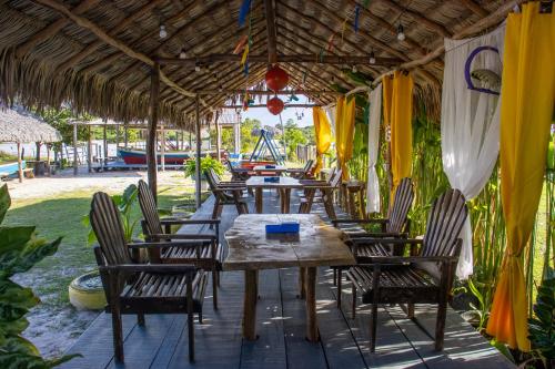 a group of tables and chairs under a thatched roof at Pousada Sol de Amaro in Santo Amaro