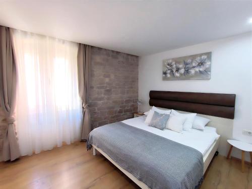 a bedroom with a large bed and a brick wall at Rialto Luxury Apartment in Šibenik