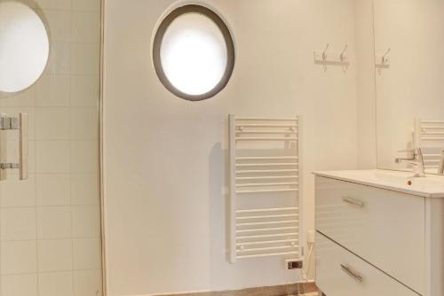 ein weißes Badezimmer mit einem Waschbecken und einem Spiegel in der Unterkunft La citadine - Abondant in Abondant
