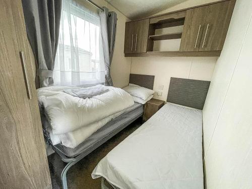 a small room with two beds and a window at Gorgeous 6 Berth Caravan With Large Decking Area, Essex Ref 44009f in Great Oakley
