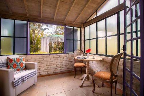 un porche cubierto con mesa, sillas y ventanas en Pousada Villa Allegra, en Tiradentes