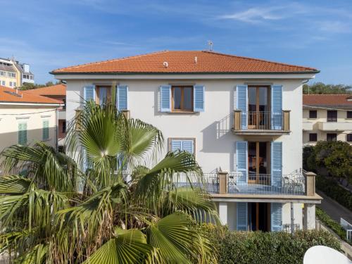 a white house with blue shutters and palm trees at Zì Maria in Marina di Cecina