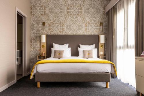 a bedroom with a large bed with yellow sheets and pillows at James Boutique Hôtel Colmar centre in Colmar