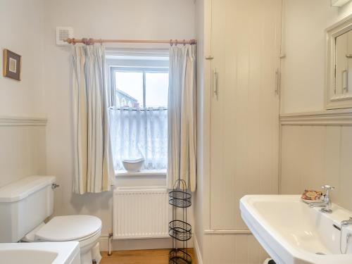 a bathroom with a toilet and a sink and a window at Gardeners Cottage in Overstrand