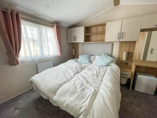 a bedroom with a large white bed with blue pillows at Stunning 6 Berth Caravan At Suffolk Sands Holiday Park Ref 45031g in Felixstowe