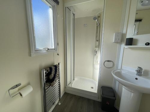 a white bathroom with a shower and a sink at Great 8 Berth Caravan At Highfield Grange, Clacton-on-sea Ref 26214o in Clacton-on-Sea
