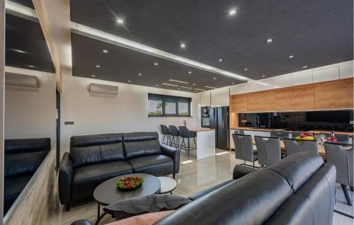a living room with black leather furniture and a kitchen at 5 Bedroom Beautiful Home In Privlaka in Privlaka