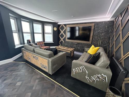 a living room with two couches and a flat screen tv at Swish Luxury Holiday Apartments in Blackpool