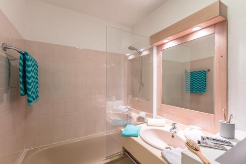 uma casa de banho com um lavatório, uma banheira e um espelho. em Résidence Pierre & Vacances Les Platanes em Sainte-Maxime