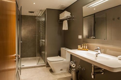 a bathroom with a toilet and a sink and a shower at Solace Hotel Santiago in Santiago