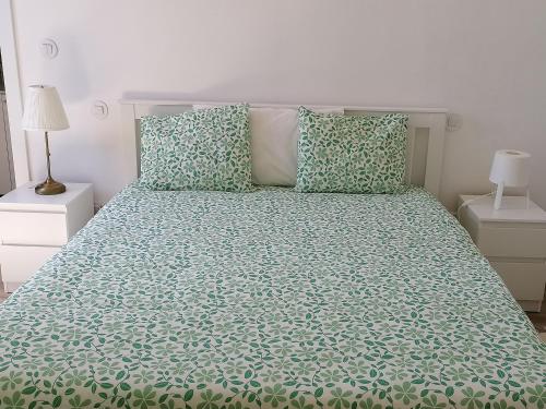 a bedroom with a bed with green sheets and pillows at A CASA DA VILA in Almodôvar