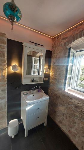 a bathroom with a sink and a mirror at Sundial Stone House in Ždrelac